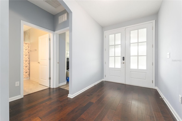 doorway to outside featuring arched walkways, french doors, dark wood finished floors, and baseboards