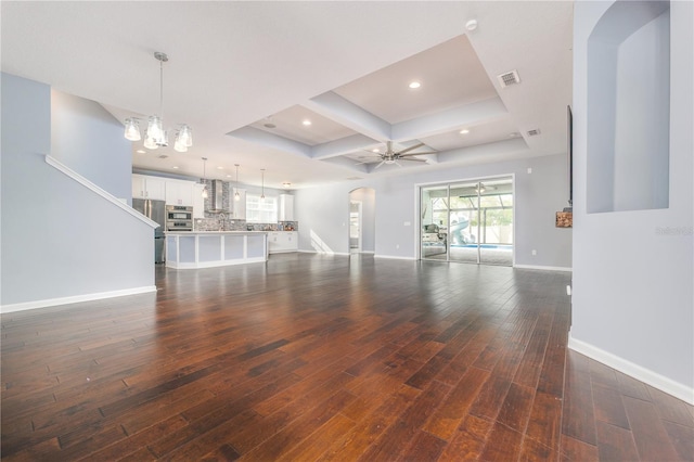 unfurnished living room featuring baseboards, visible vents, arched walkways, wood finished floors, and recessed lighting