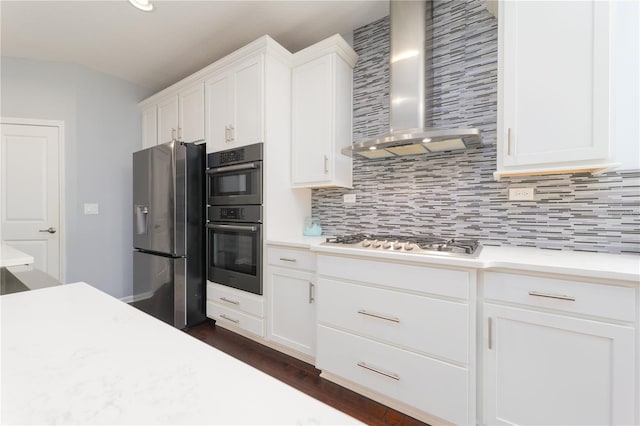 kitchen with stainless steel appliances, light countertops, white cabinets, and wall chimney range hood