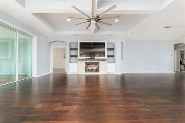 unfurnished living room with arched walkways, wood-type flooring, a raised ceiling, and baseboards