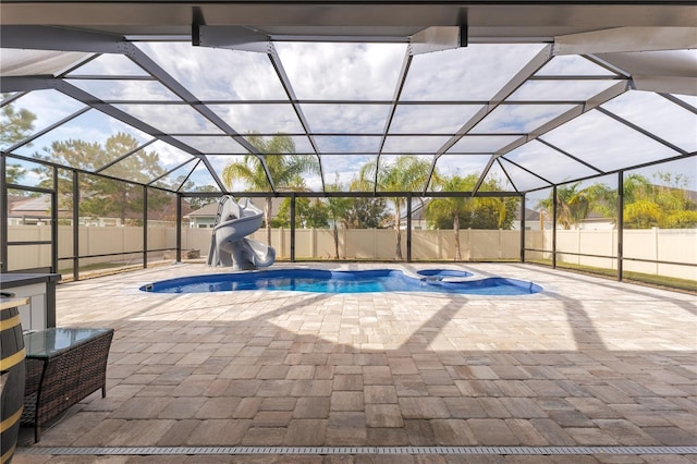 view of swimming pool featuring a lanai, a patio area, a fenced backyard, and a water slide