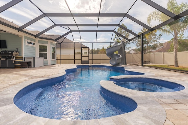 view of pool with a water slide, a fenced backyard, area for grilling, a pool with connected hot tub, and a patio area