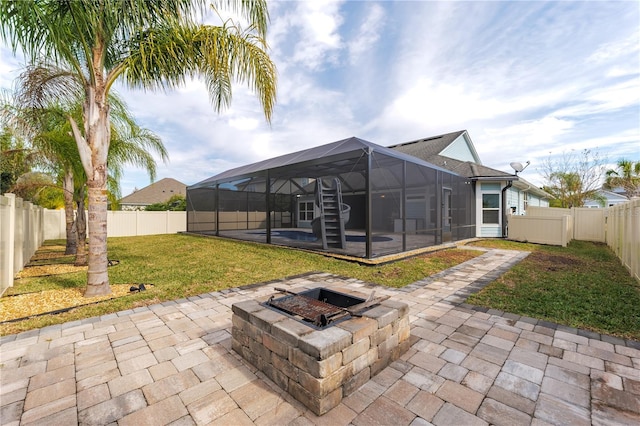 back of house with a fire pit, a patio area, a fenced backyard, and glass enclosure