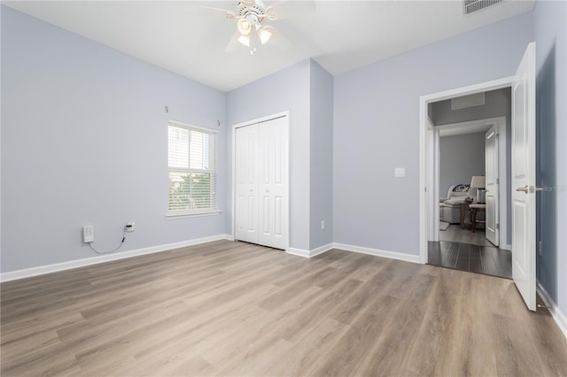 unfurnished bedroom featuring visible vents, a closet, baseboards, and wood finished floors