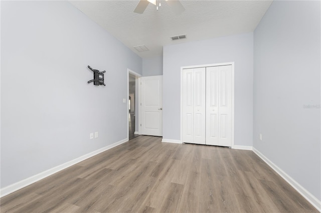 unfurnished bedroom with baseboards, a closet, visible vents, and wood finished floors