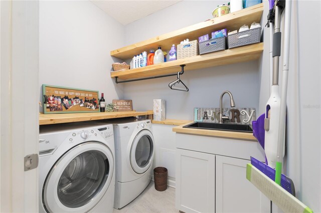 washroom featuring cabinet space, separate washer and dryer, and a sink