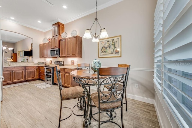 kitchen with decorative light fixtures, ornamental molding, stainless steel appliances, and an inviting chandelier