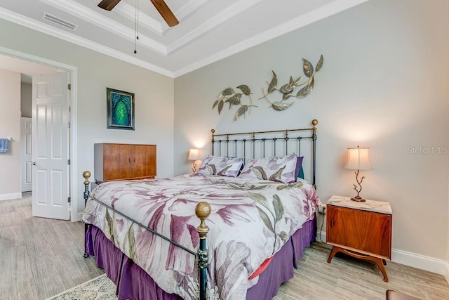 bedroom featuring a raised ceiling, ceiling fan, wood-type flooring, and ornamental molding