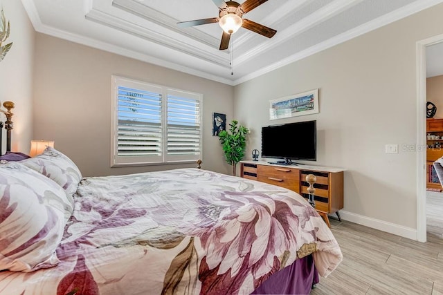 bedroom with ceiling fan, a raised ceiling, crown molding, and light hardwood / wood-style flooring