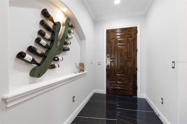 foyer with dark tile patterned floors and ornamental molding