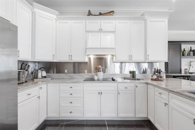 kitchen featuring stainless steel refrigerator, light stone countertops, black electric stovetop, and white cabinets