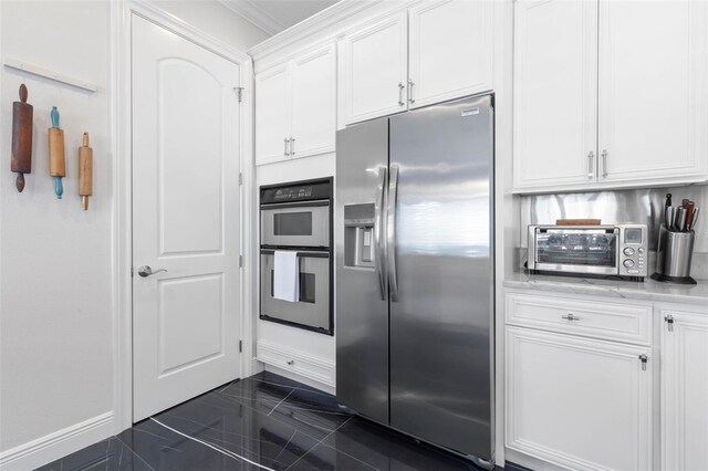 kitchen with stainless steel appliances, white cabinetry, and ornamental molding