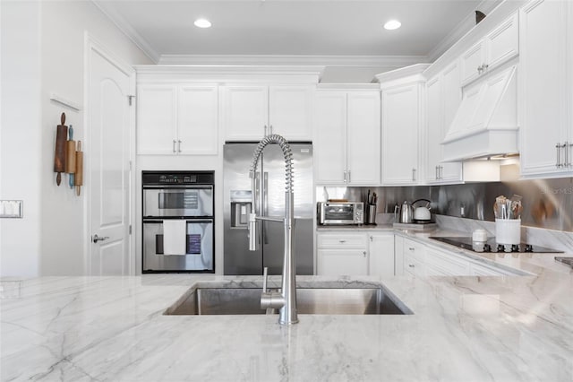 kitchen featuring light stone countertops, appliances with stainless steel finishes, premium range hood, and white cabinetry