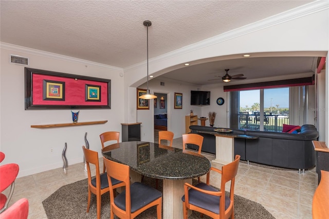 dining space with ceiling fan, light tile patterned floors, a textured ceiling, and ornamental molding