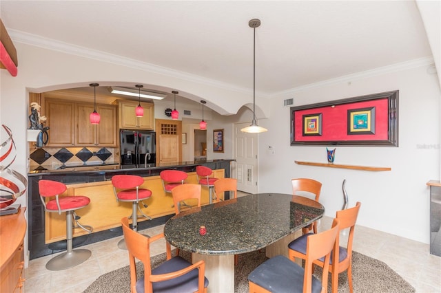 tiled dining space featuring crown molding