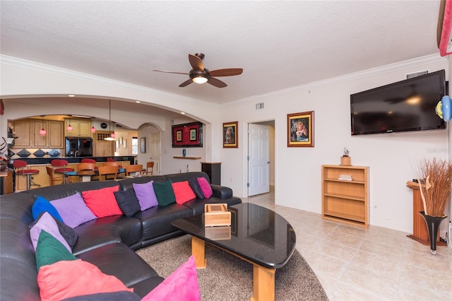 tiled living room with ceiling fan, a textured ceiling, and ornamental molding