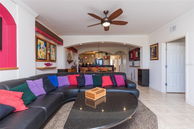 living room featuring ceiling fan, light tile patterned flooring, ornamental molding, and a textured ceiling