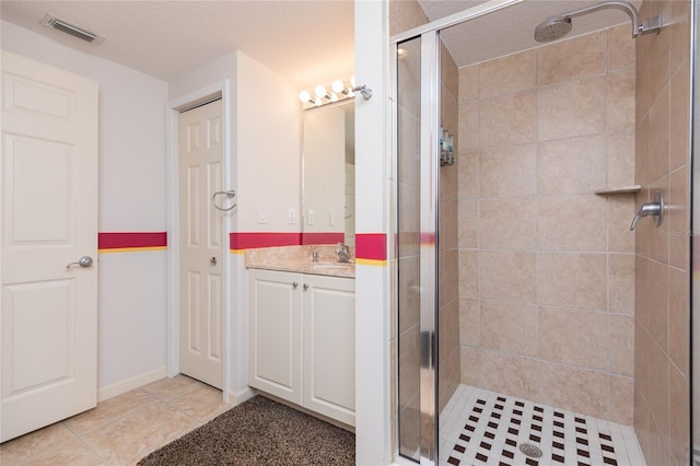 bathroom with tile patterned flooring, vanity, an enclosed shower, and a textured ceiling