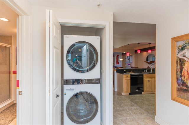 laundry area with light tile patterned flooring and stacked washer and dryer