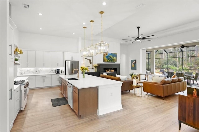 kitchen featuring white cabinetry, sink, hanging light fixtures, a kitchen island with sink, and appliances with stainless steel finishes