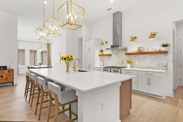 kitchen featuring white cabinets, pendant lighting, wall chimney exhaust hood, and sink