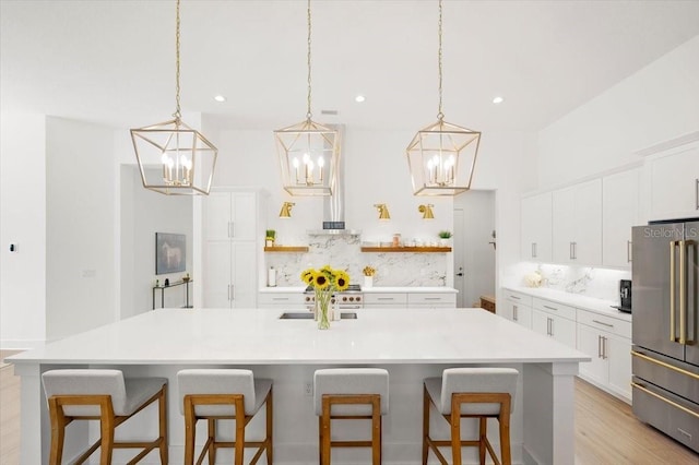 kitchen featuring a kitchen bar, pendant lighting, tasteful backsplash, and high end fridge