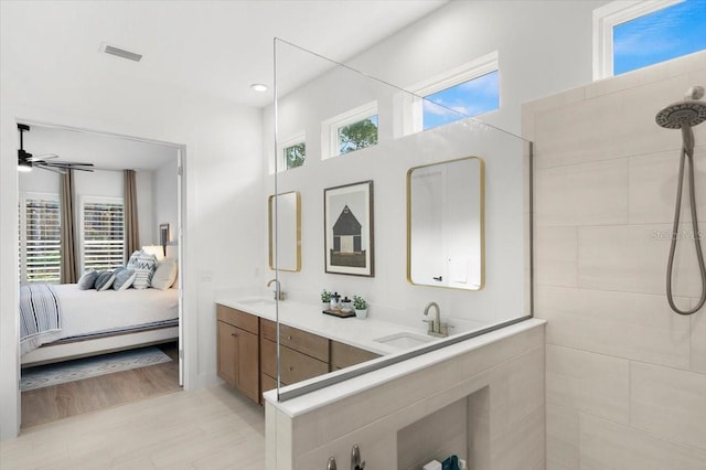 bathroom with ceiling fan, vanity, a healthy amount of sunlight, and tiled shower