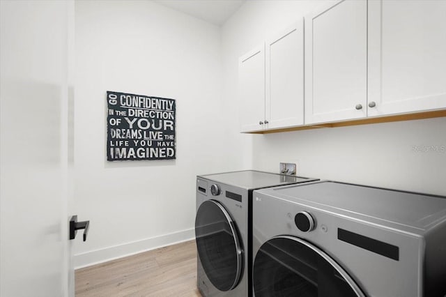 clothes washing area with cabinets, separate washer and dryer, and light hardwood / wood-style flooring