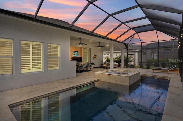 pool at dusk featuring a patio, a hot tub, ceiling fan, and a lanai