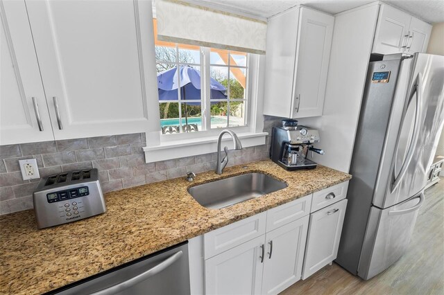 kitchen with appliances with stainless steel finishes, white cabinetry, and sink