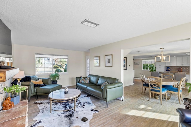 living room featuring light wood-type flooring, an inviting chandelier, and a wealth of natural light