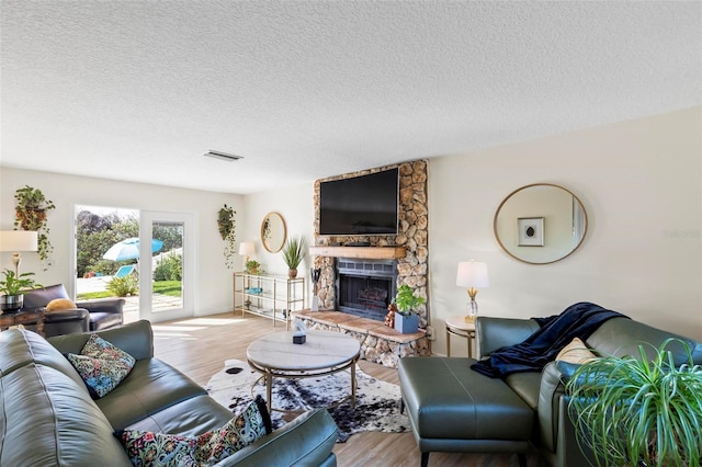 living room with a fireplace, a textured ceiling, and light hardwood / wood-style flooring