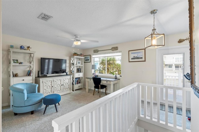 carpeted living room featuring ceiling fan and a textured ceiling