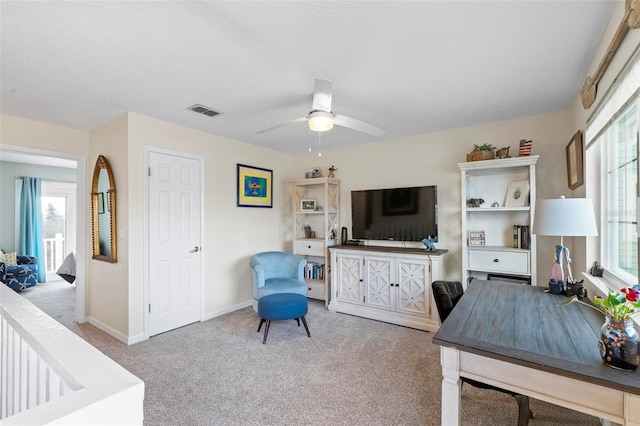 carpeted office space with ceiling fan