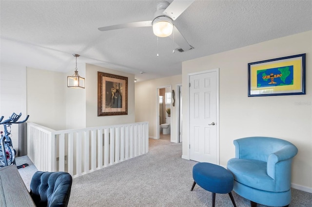 living area with ceiling fan, light colored carpet, and a textured ceiling