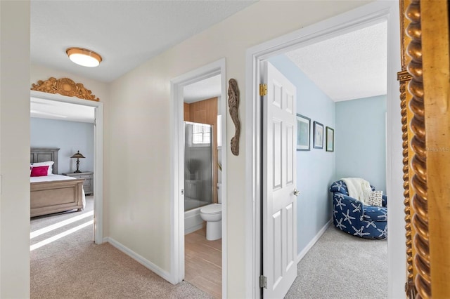 corridor featuring a textured ceiling and light colored carpet