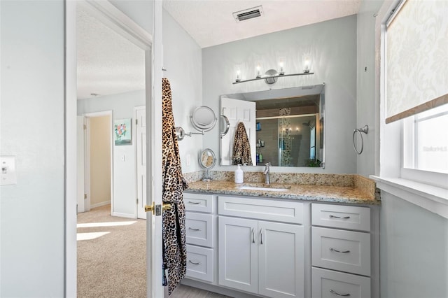 bathroom with vanity, a shower with shower door, and a textured ceiling