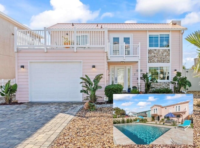 exterior space with french doors, metal roof, decorative driveway, and a balcony