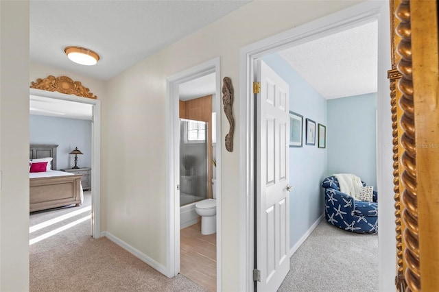 corridor featuring carpet flooring, a textured ceiling, and baseboards