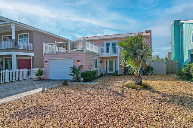 view of front facade with fence, french doors, decorative driveway, an attached garage, and a gate
