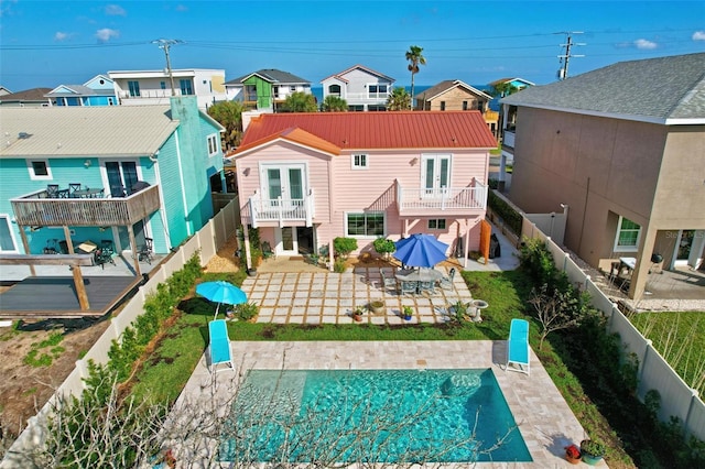 rear view of house featuring french doors, a residential view, a balcony, and a fenced backyard