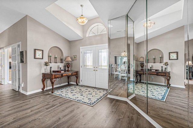 foyer entrance with a towering ceiling, french doors, a chandelier, and dark hardwood / wood-style floors