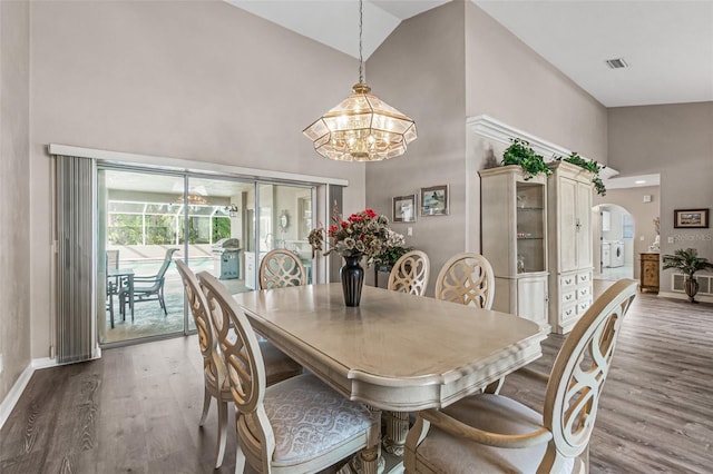 dining area with a notable chandelier, high vaulted ceiling, and hardwood / wood-style flooring