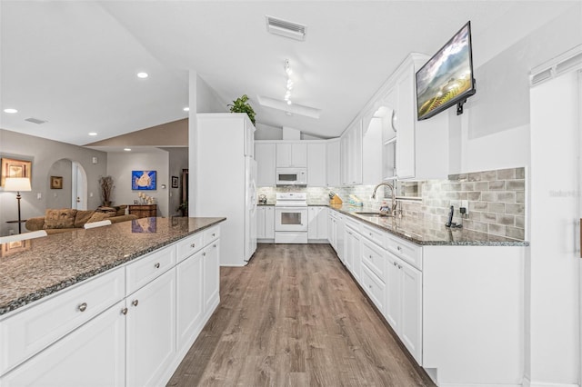 kitchen with sink, white cabinets, white appliances, backsplash, and dark stone counters