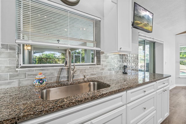 kitchen featuring white cabinetry, dark hardwood / wood-style floors, dark stone countertops, and sink