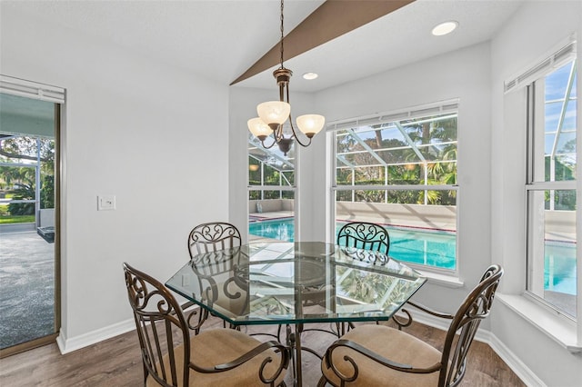 dining room featuring lofted ceiling, dark wood-type flooring, an inviting chandelier, and a healthy amount of sunlight