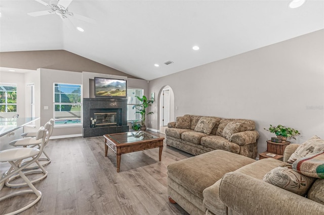 living room with ceiling fan, light wood-type flooring, and vaulted ceiling