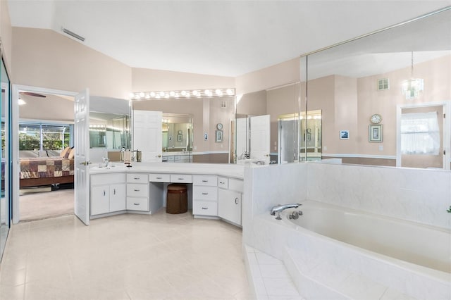 bathroom featuring lofted ceiling, tile patterned floors, tiled tub, and vanity