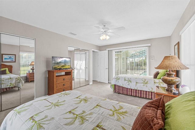 bedroom with multiple closets, ceiling fan, and light colored carpet