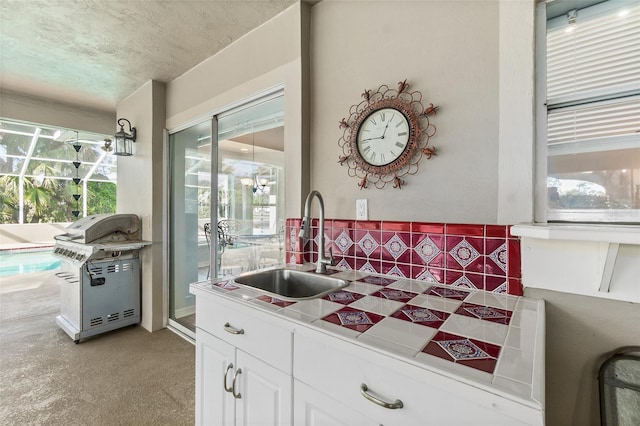 kitchen with white cabinets, light carpet, decorative backsplash, and sink